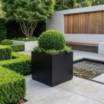 Czarna metalowa donica kwadratowa do ogrodu z bukszpanem w nowoczesnej aranżacji