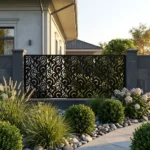 Czarny metalowy panel ogrodzeniowy z dekoracyjnym ażurowym wzorem zamontowany między murowanymi słupkami przed nowoczesnym domem.