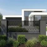 Czarny metalowy panel ogrodzeniowy z eleganckim ażurowym wzorem liści zamontowany przed nowoczesnym domem.