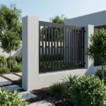 Metalowy panel ogrodzeniowy w ciemnym kolorze z nowoczesnym geometrycznym wzorem zamontowany między jasnymi słupkami przy minimalistycznej posesji.
