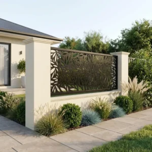 Metalowy panel ogrodzeniowy w ciemnym kolorze z ażurowym wzorem liści zamontowany między jasnymi słupkami przy nowoczesnym domu.