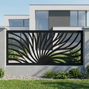 Metalowy panel ogrodzeniowy w czarnym kolorze z dynamicznym ażurowym wzorem promieni zamontowany między jasnymi słupkami przy nowoczesnym domu.