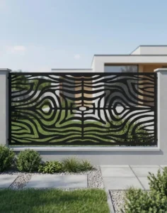 Metalowy panel ogrodzeniowy w czarnym kolorze z dynamicznym ażurowym wzorem falistych linii zamontowany między jasnymi słupkami przy nowoczesnym domu.