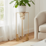 Stojak metalowy na kwiaty w złotym kolorze z ozdobnymi motywami w narożnikach, elegancki element dekoracyjny do wnętrz.