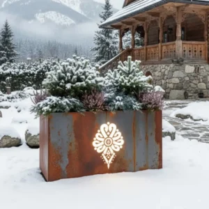 Metalowa donica LED z góralskim wzorem i podświetlanym logo przed góralską chatą w zimowej scenerii.
