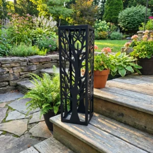 Kolumna ogrodowa metalowa „Drzewo Życia” z ażurowym motywem pnia i gałęzi ustawiona przy drewnianych schodach w ogrodzie