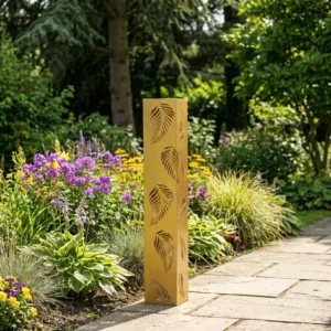 Złota kolumna ogrodowa metalowa „Złota Aleja” z wyciętym motywem liści ustawiona przy ścieżce w ogrodzie