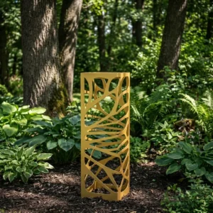 Złota kolumna ogrodowa metalowa „Złoty Splot” z ażurowym, organicznym wzorem ustawiona wśród roślin leśnego ogrodu