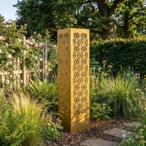 Złota kolumna ogrodowa metalowa „Złota Mozaika” z geometrycznym, ażurowym wzorem ustawiona w ogrodzie przy rabatach