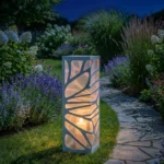 Metalowy lampion ogrodowy Złoty Splot z ażurowym wzorem w nocnej aranżacji ogrodu