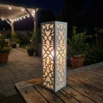 Metalowy lampion ogrodowy Serce Ogrodu z romantycznym ażurowym wzorem w nocnej aranżacji ogrodu