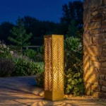 Metalowy lampion ogrodowy Harmonia Liści z botanicznym ażurowym wzorem w nocnej aranżacji ogrodu