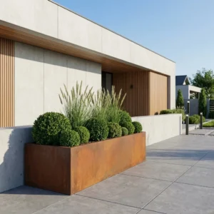 Cortenowa metalowa donica prostokątna do ogrodu z trawami ozdobnymi i krzewami przy nowoczesnym domu