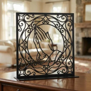 Dłonie Modlitwy w Ramie – metalowa dekoracja wolnostojąca ustawiona na drewnianej komodzie w eleganckim wnętrzu