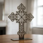 Krzyż Gotycki Ornament – metalowa dekoracja wolnostojąca ustawiona na drewnianym stole w jasnym wnętrzu