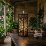 Lampion Liść Płomień – biały metalowy lampion z ażurowym wzorem liści ustawiony na tarasie