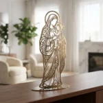 Matka Boża z Dzieciątkiem – metalowa dekoracja wolnostojąca w kolorze złotym ustawiona na komodzie